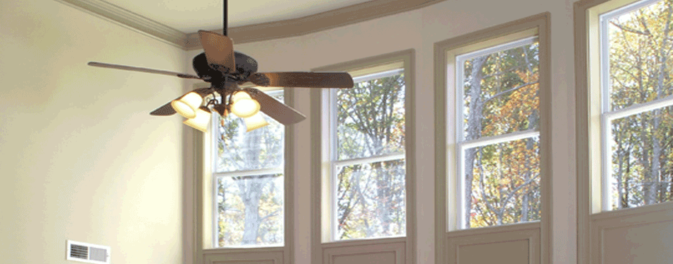 A ceiling fan in the middle of two windows.